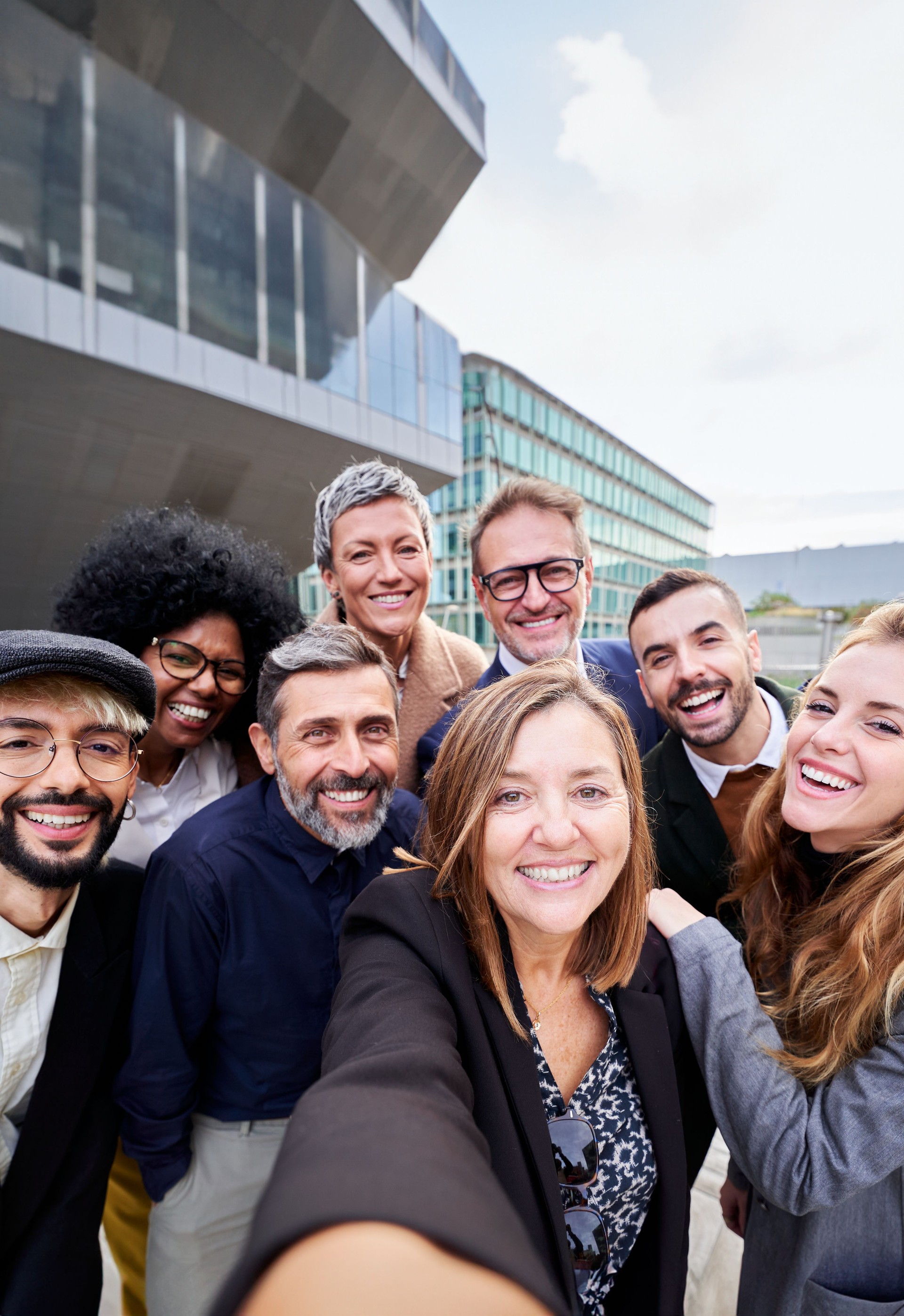 Group of multiracial business people taking a selfie together, looking at the camera smiling.